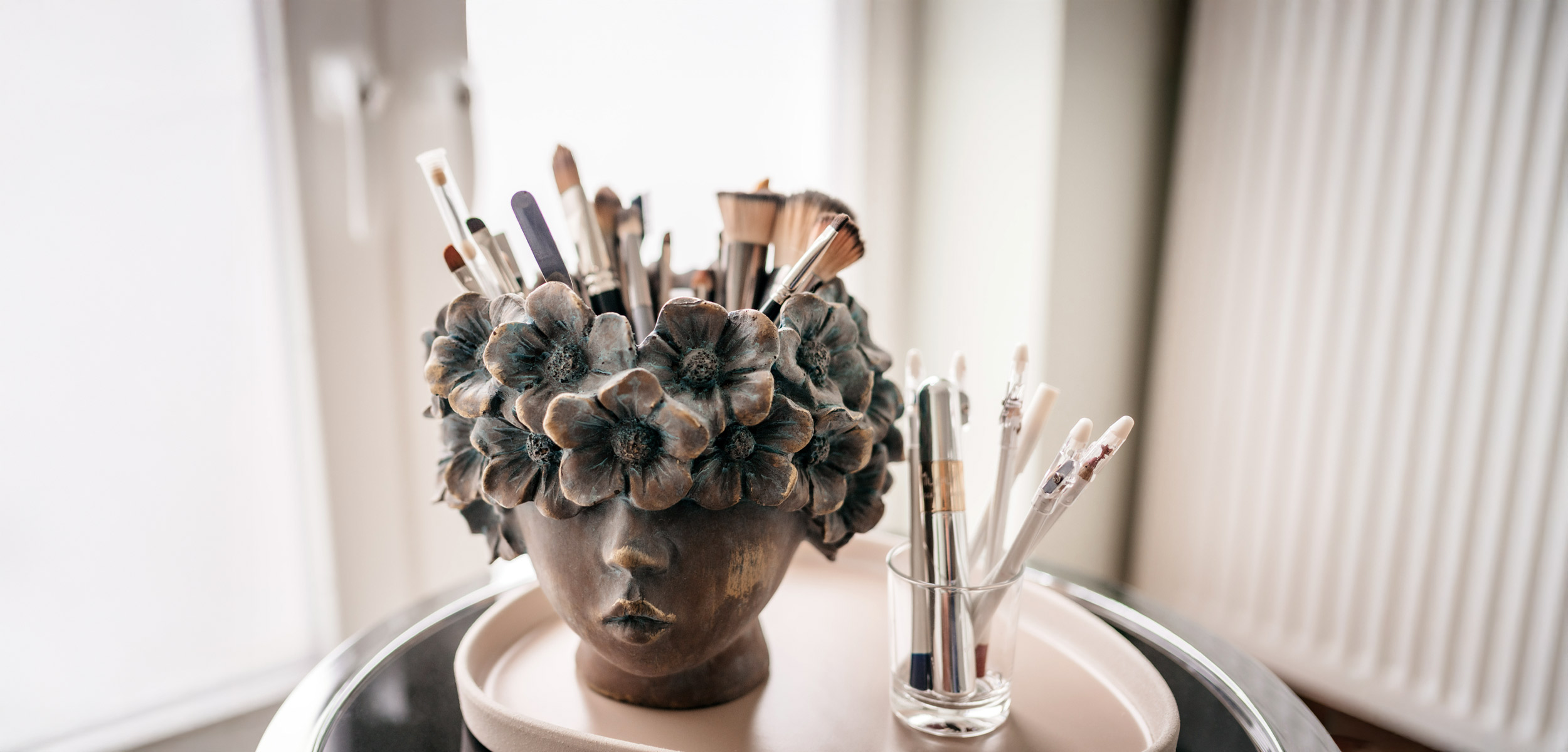 Make-up-Pinsel in einer Vase mit Gesichts- und Blütenmotiv